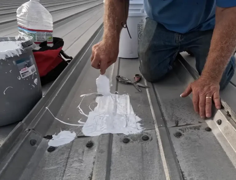 A roofer applies white sealant over a row of fasteners on a corrugated metal roof, addressing a visible warning sign before it leaks